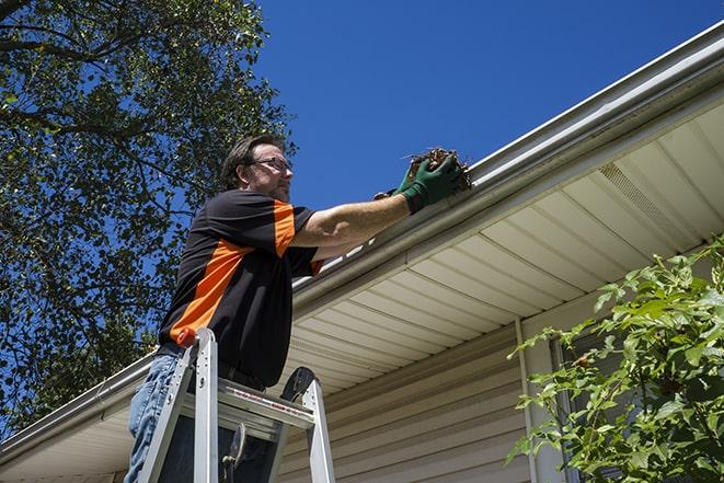 a skilled worker fixing broken gutter on a roof in Beltsville MD